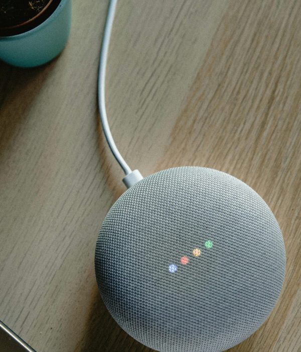 A top view of a smart speaker with a glowing indicator on a desk, emphasizing modern technology.